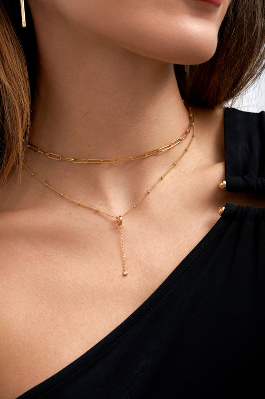 Woman wearing simple gold vermeil necklace stack with lab grown diamond add-on charm. L'ERA Jewellery