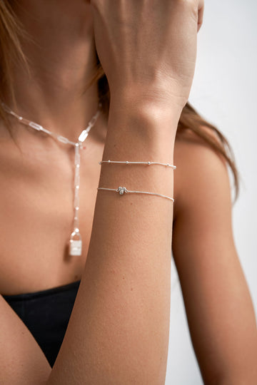 Woman wearing Sterling Silver bracelet stack and paperclip necklace with Terza lab grown diamond pendant.