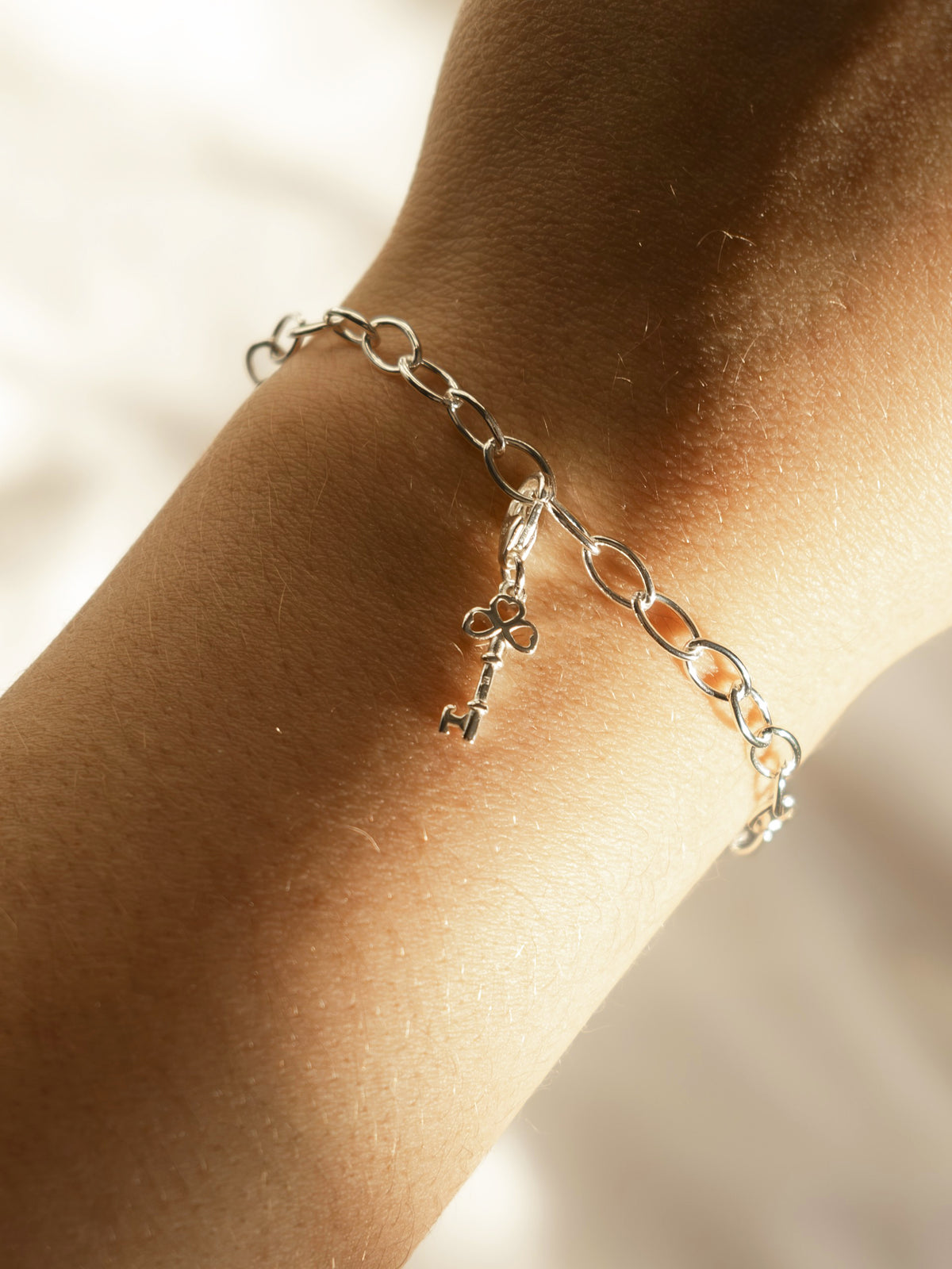 model wearing key charm on bracelet  in silver