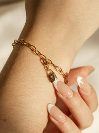 model wearing lock charm on bracelet in gold